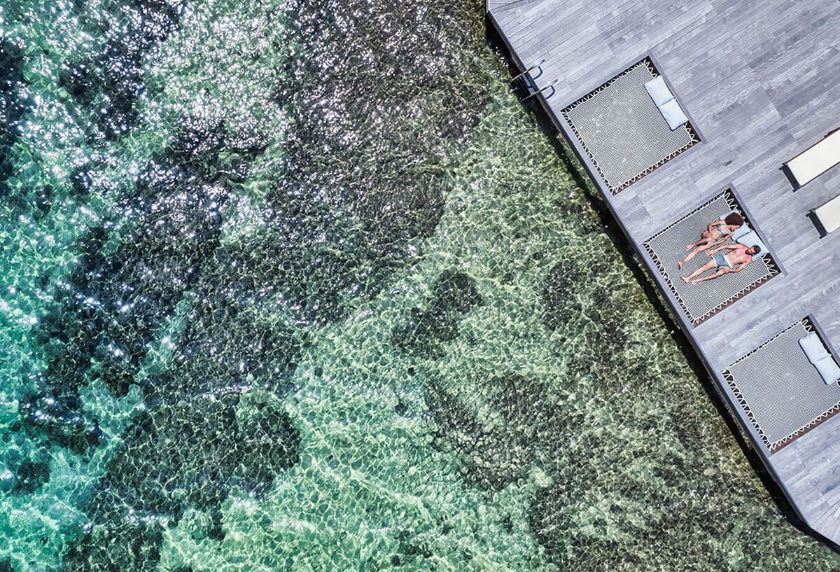 A clear view of a swimming pool with a wooden deck and lounge chairs.