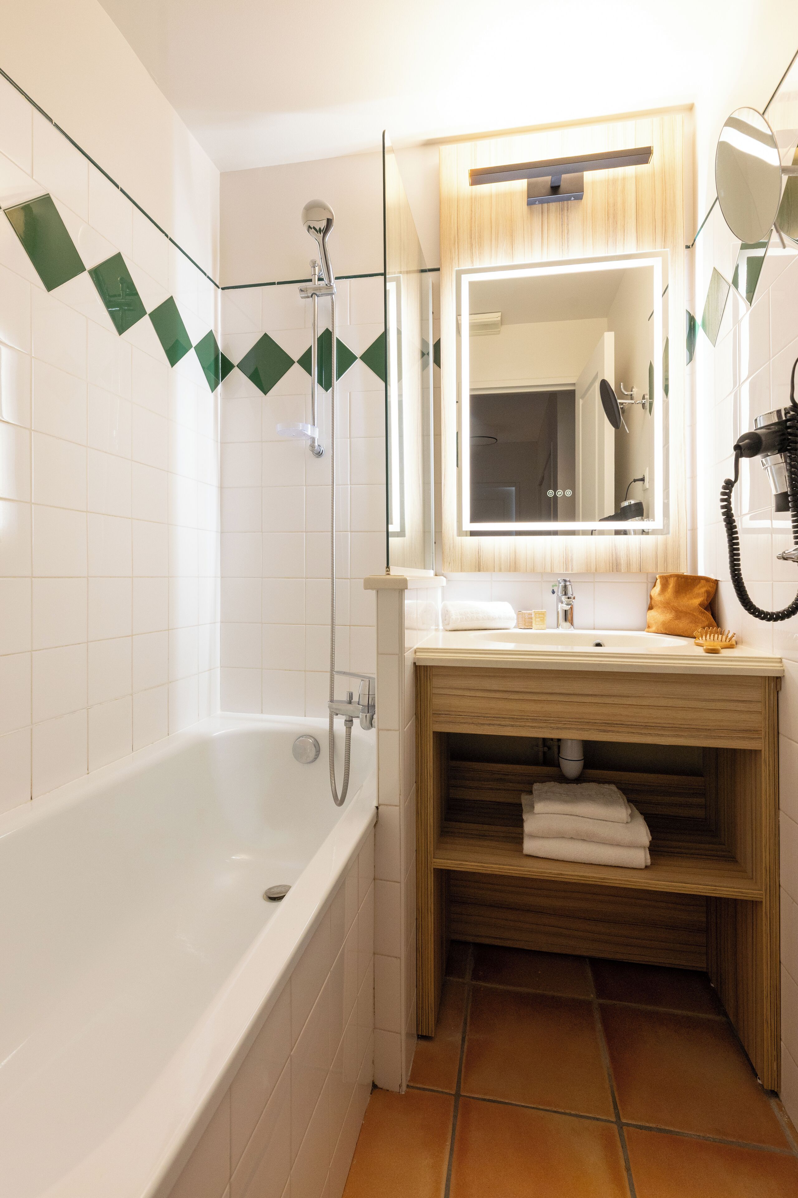 Un baño con bañera, un lavabo con espejo y un perchero para toallas.