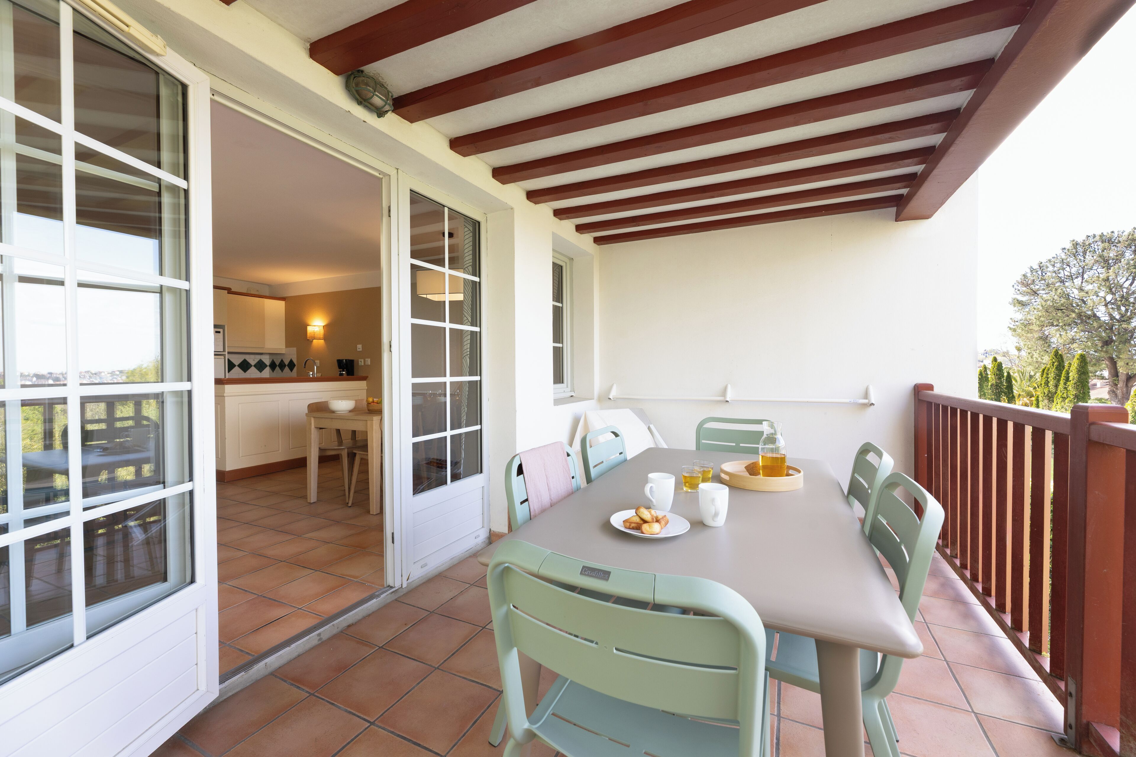 A dining area with a table set for four, chairs, and a view of the kitchen and balcony.