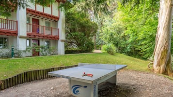 Una mesa de ping pong en un jardín con un edificio al fondo.