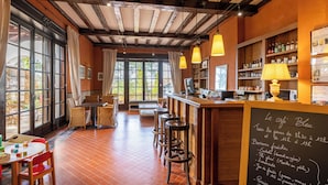 A cozy cafe with exposed wooden beams, a bar area, and a seating section with tables and chairs.