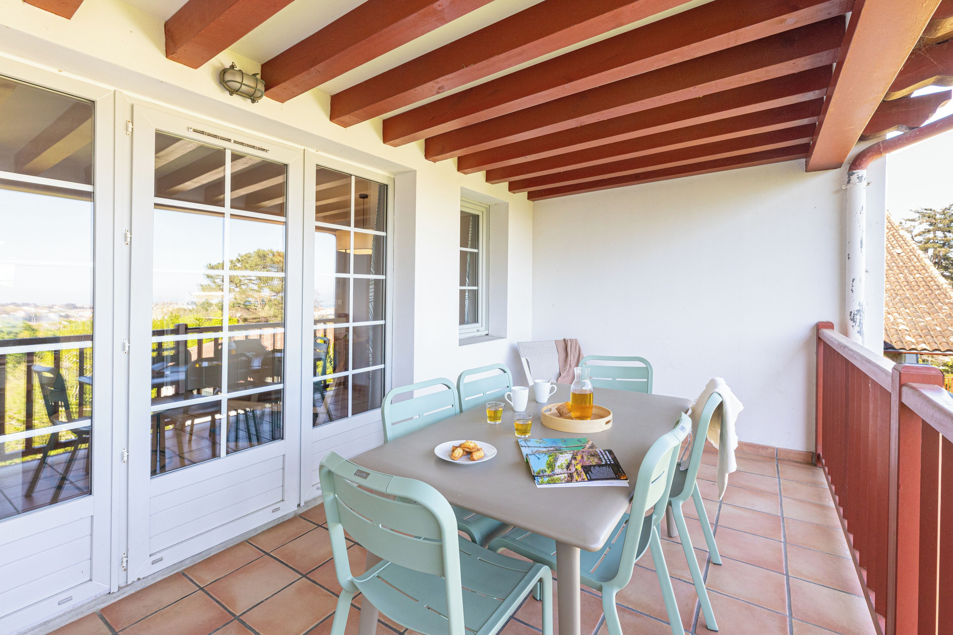 Un balcón con una mesa para dos, sillas y vistas al exterior.