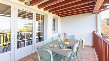 Un balcón con una mesa para dos, sillas y vistas al exterior.