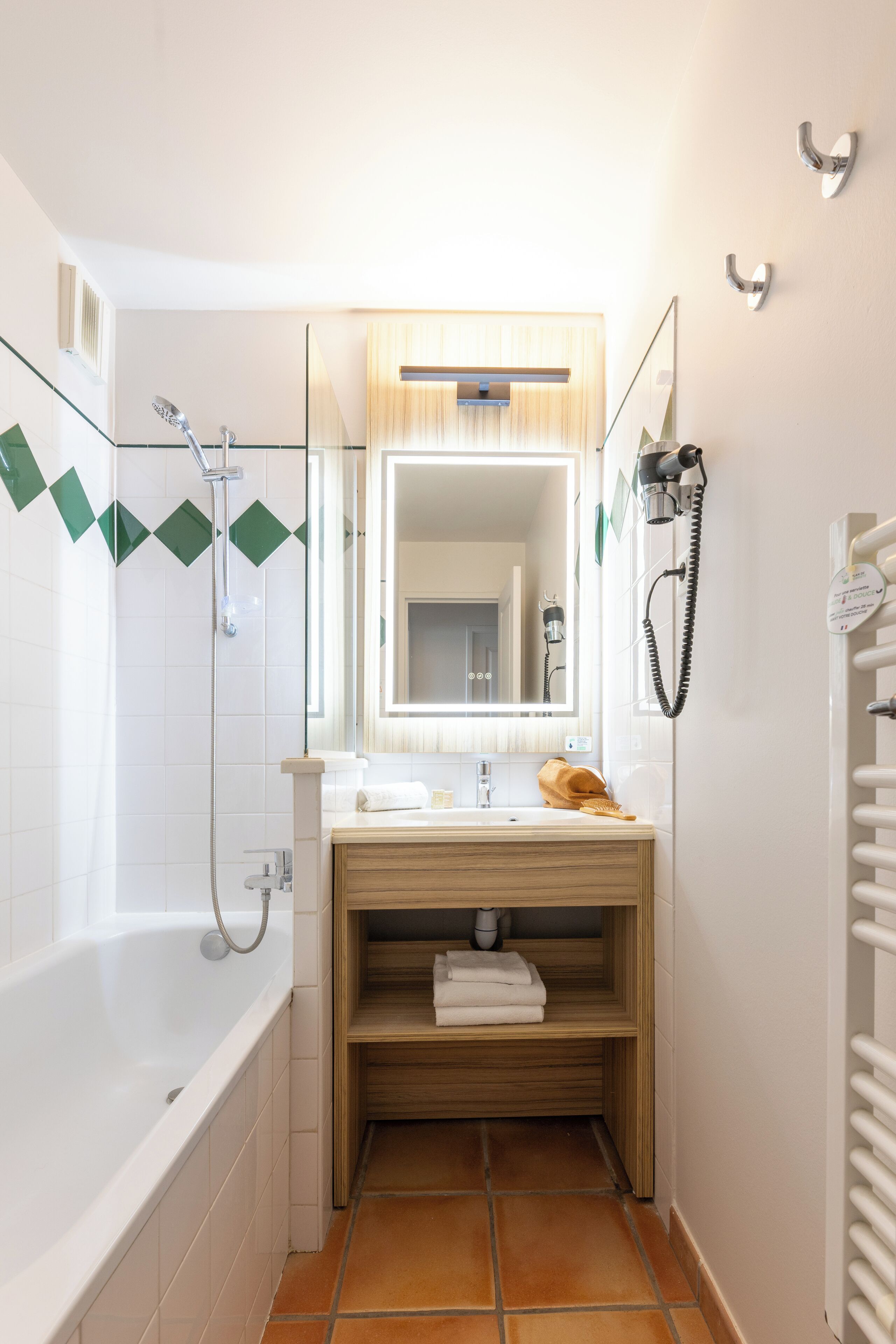 Une salle de bain équipée d’une baignoire, d’un lavabo, d’un miroir, d’un porte-serviettes et d’une douche.