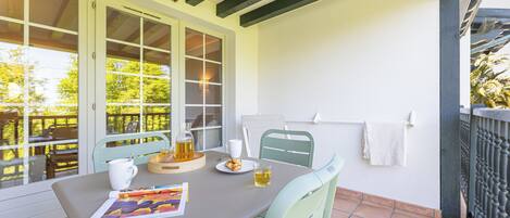 A patio with a table set for two, featuring a white mug, a glass of beer, and a plate of cookies.
