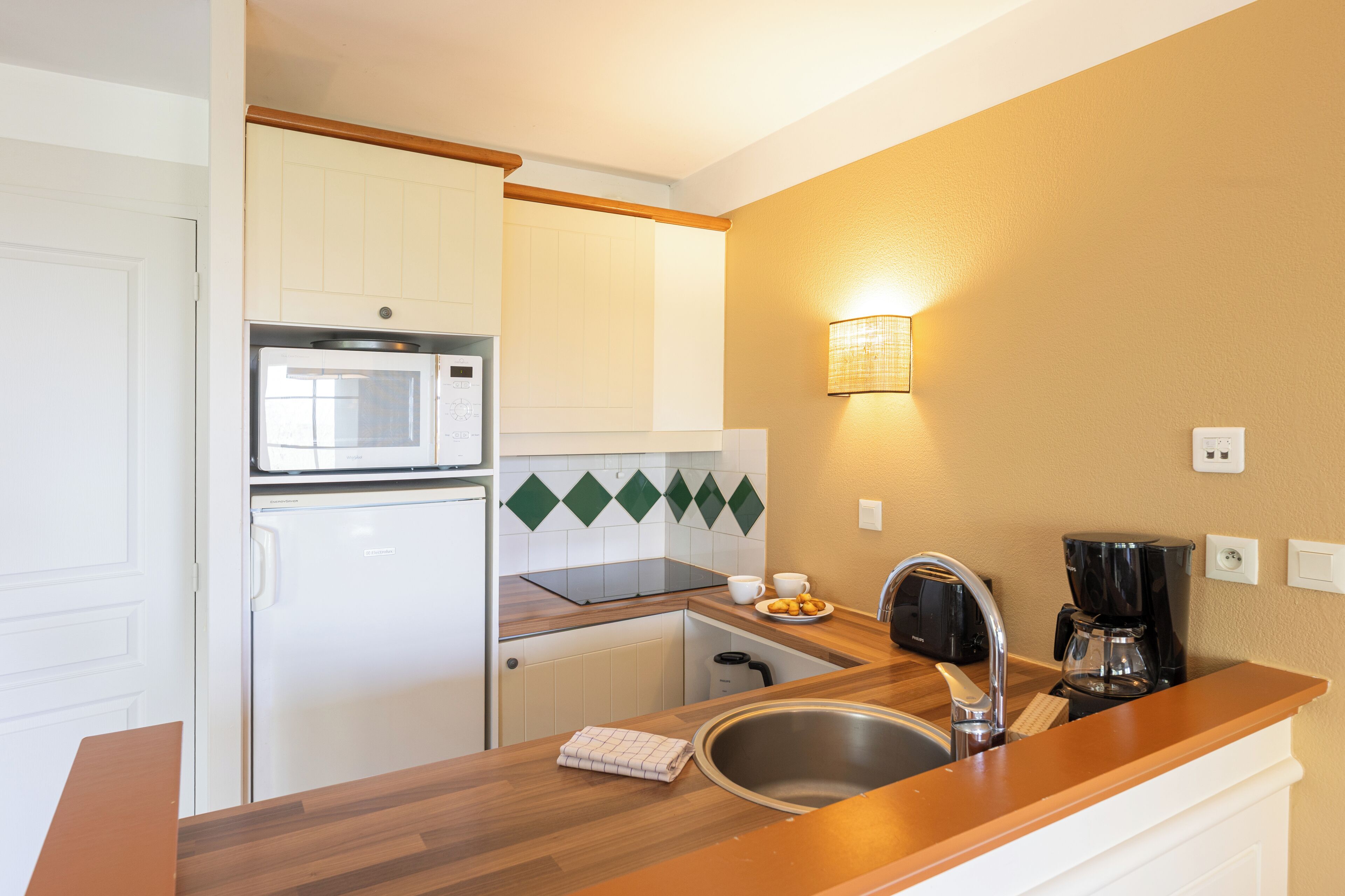 A compact kitchenette with a microwave, refrigerator, sink, and a coffee maker.