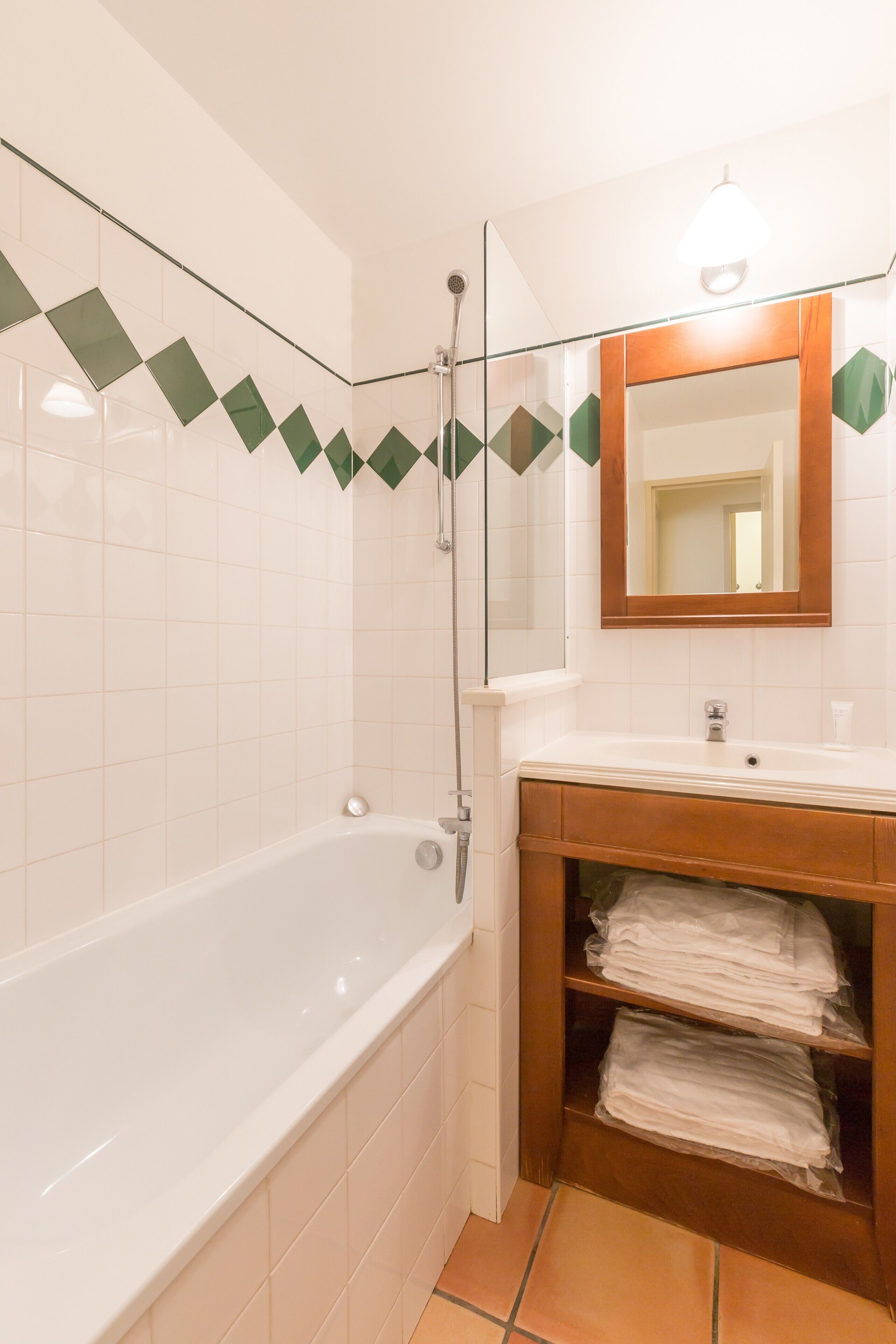 Ein Badezimmer mit einer Badewanne, einem Waschbecken, einem Spiegel und einem Handtuchhalter.