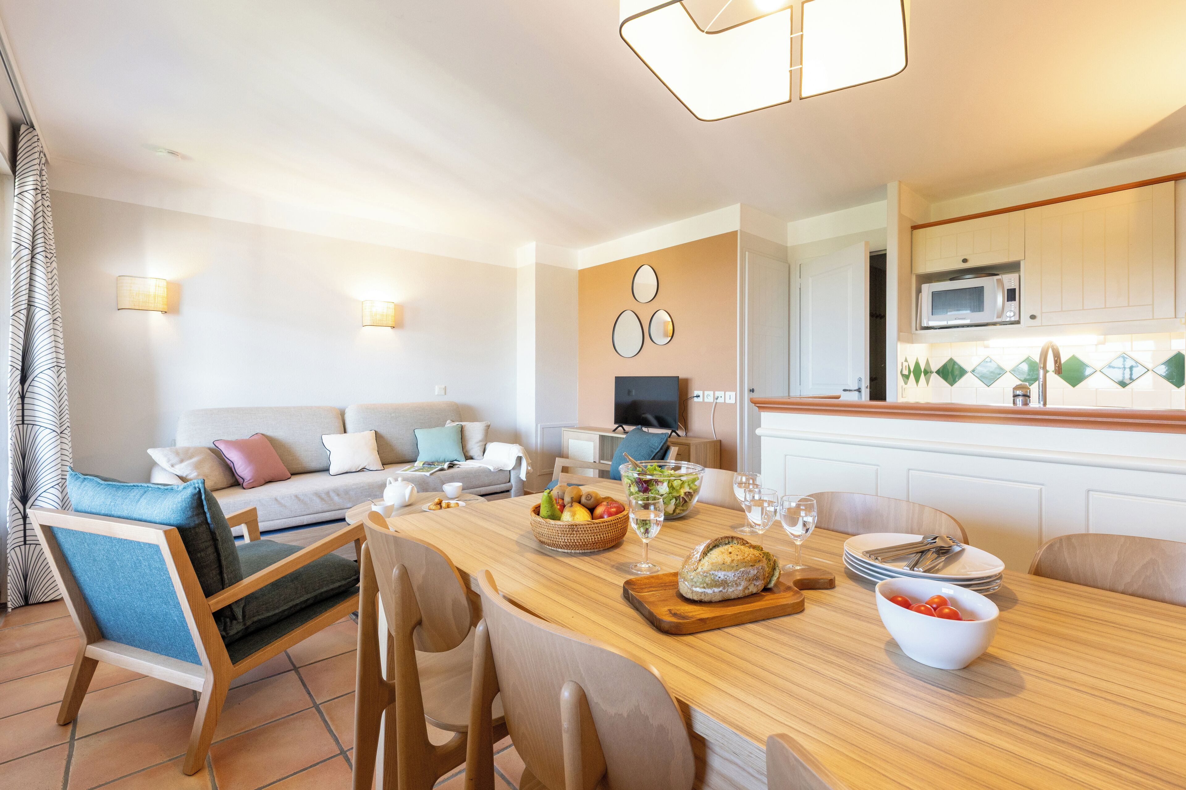 Una cocina moderna con una mesa de comedor de madera, sillas y un microondas.