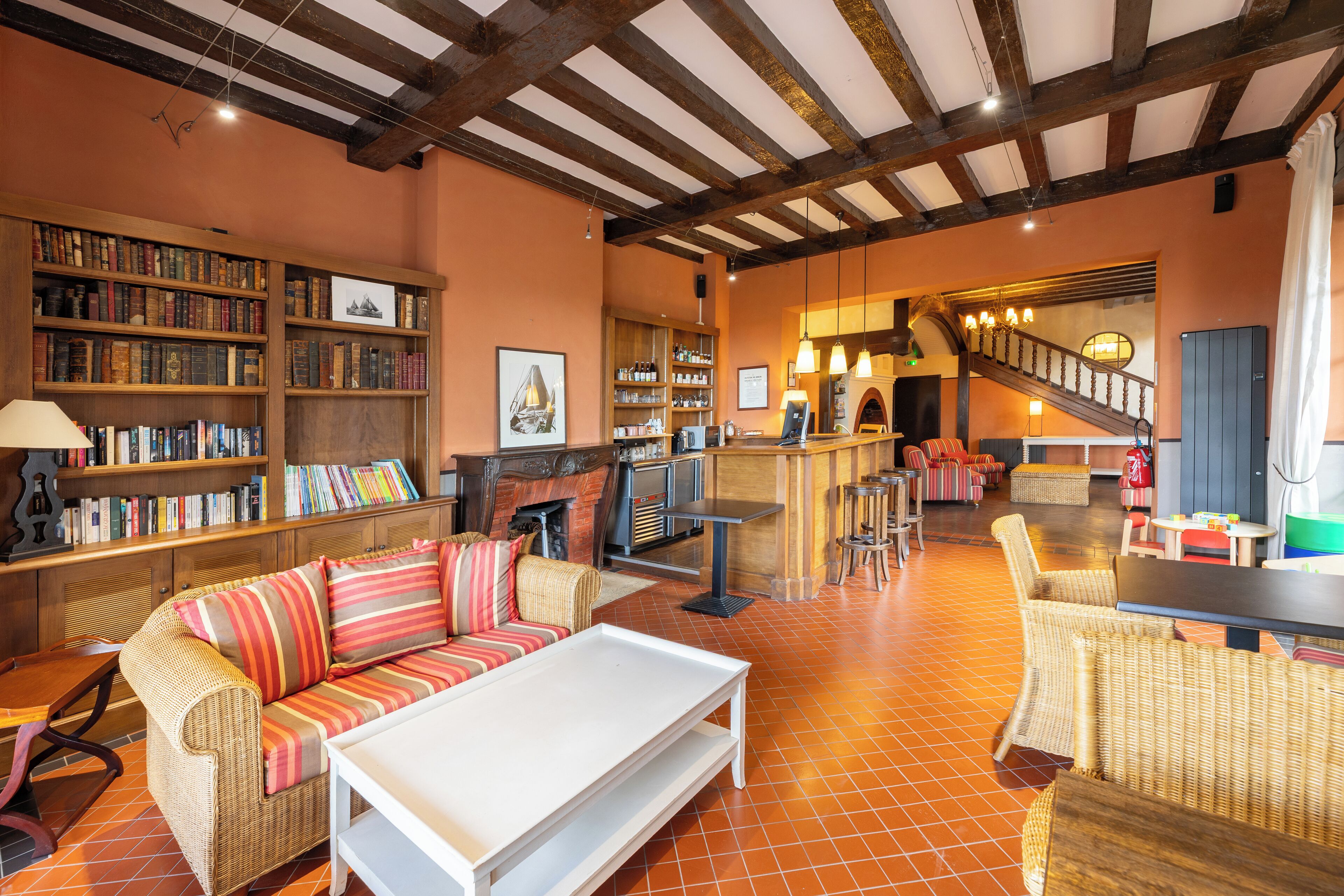 A cozy library with bookshelves, a fireplace, and a staircase leading to another level.