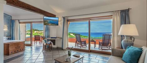 A spacious living area with a large sliding glass door leading to a balcony with a view of the sea.