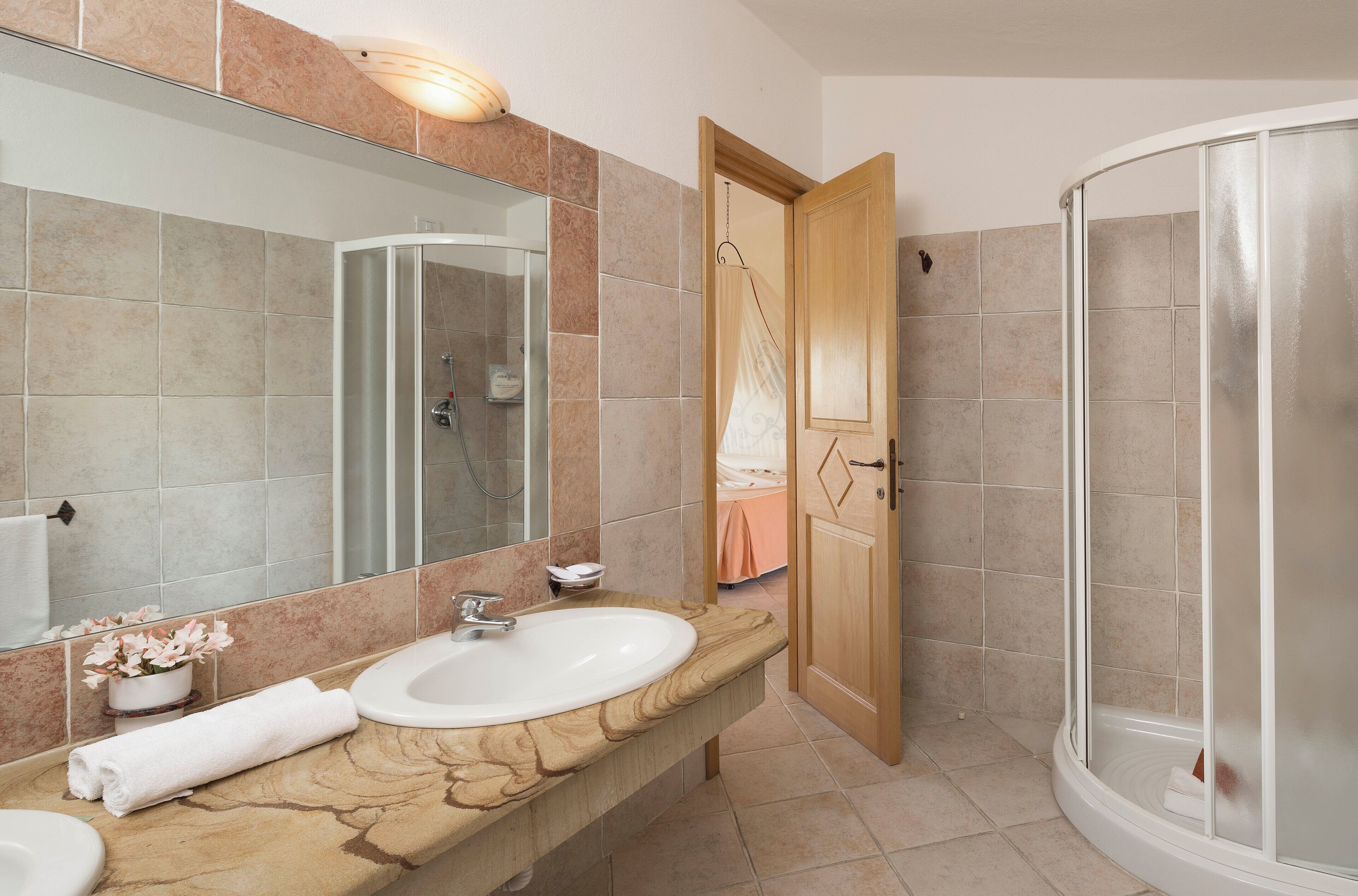 Un baño con un espejo grande, dos lavamanos, cabina de ducha y toallero.