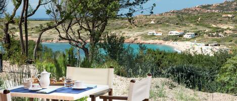Mesa al aire libre con vista a la playa y colinas.