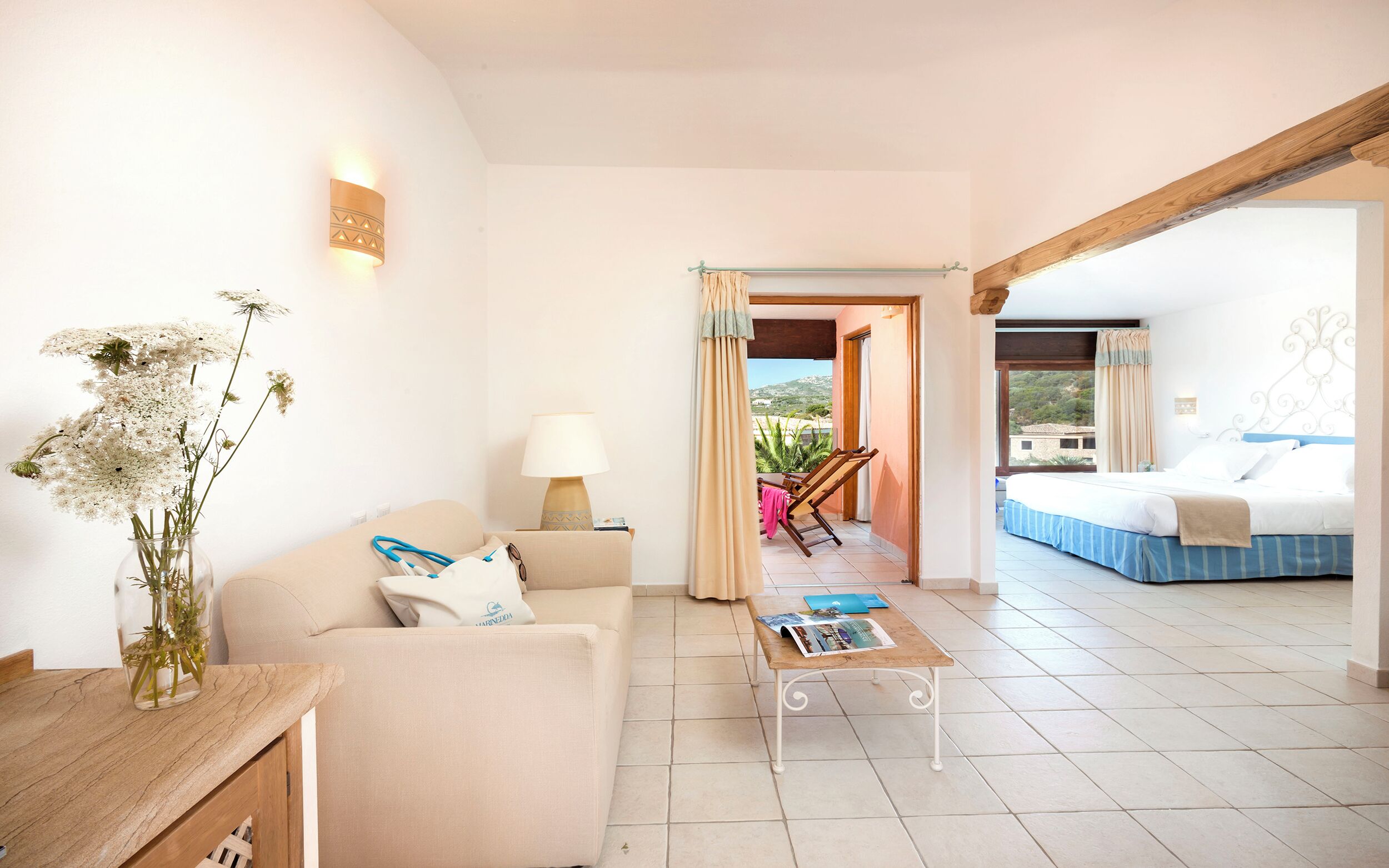 Habitación de hotel con sofá, mesa de centro, lámpara, cama y vistas al exterior.