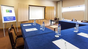 Un salón de conferencias con mesas dispuestas para reuniones, equipado con botellas de agua y blocs de notas.