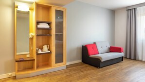 Une pièce avec une armoire en bois, un canapé avec des coussins rouges et un miroir avec un éclairage intégré.