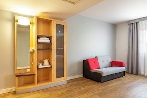 Une pièce avec une armoire en bois, un canapé avec des coussins rouges et un miroir avec un éclairage intégré.