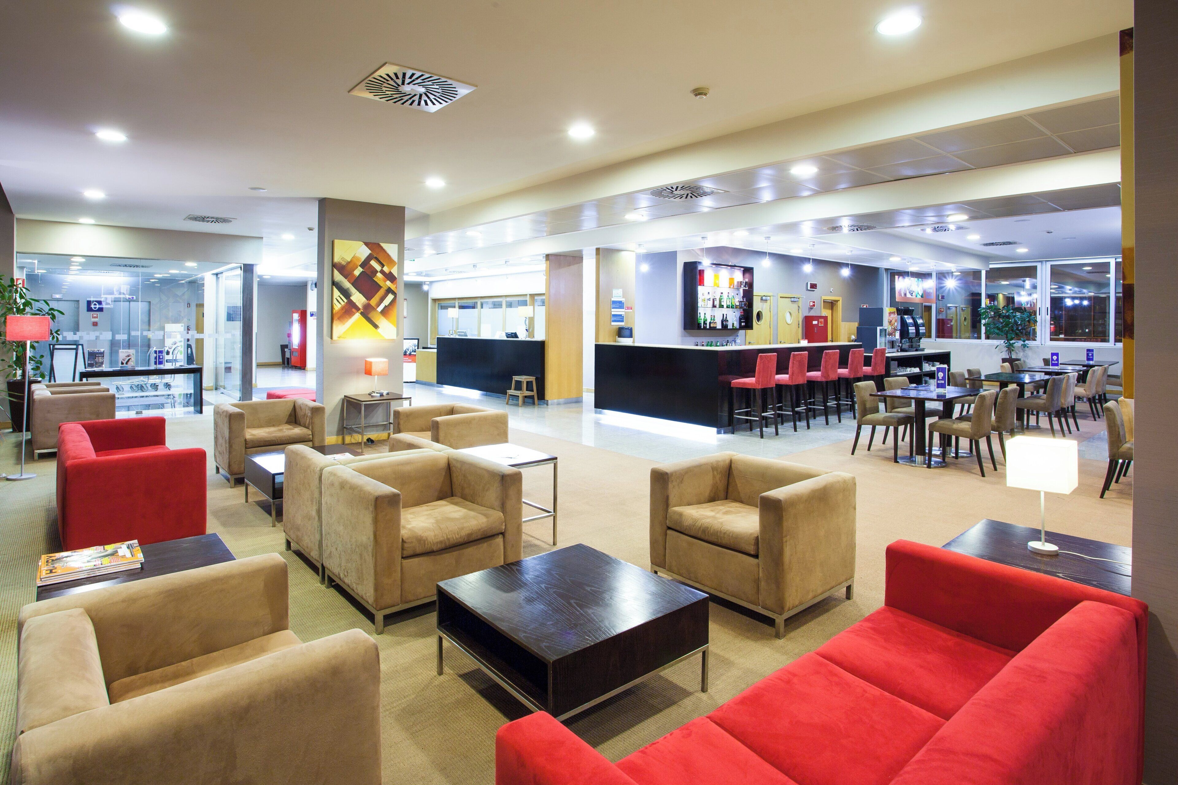 A hotel lobby with seating areas, a reception desk, and a bar.