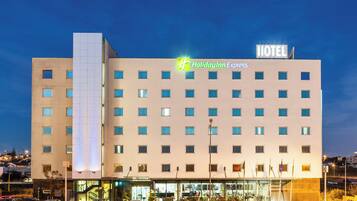 Ein Holiday Inn Express Hotel mit moderner Fassade, zahlreichen Fenstern und einem Parkplatz mit mehreren Autos.