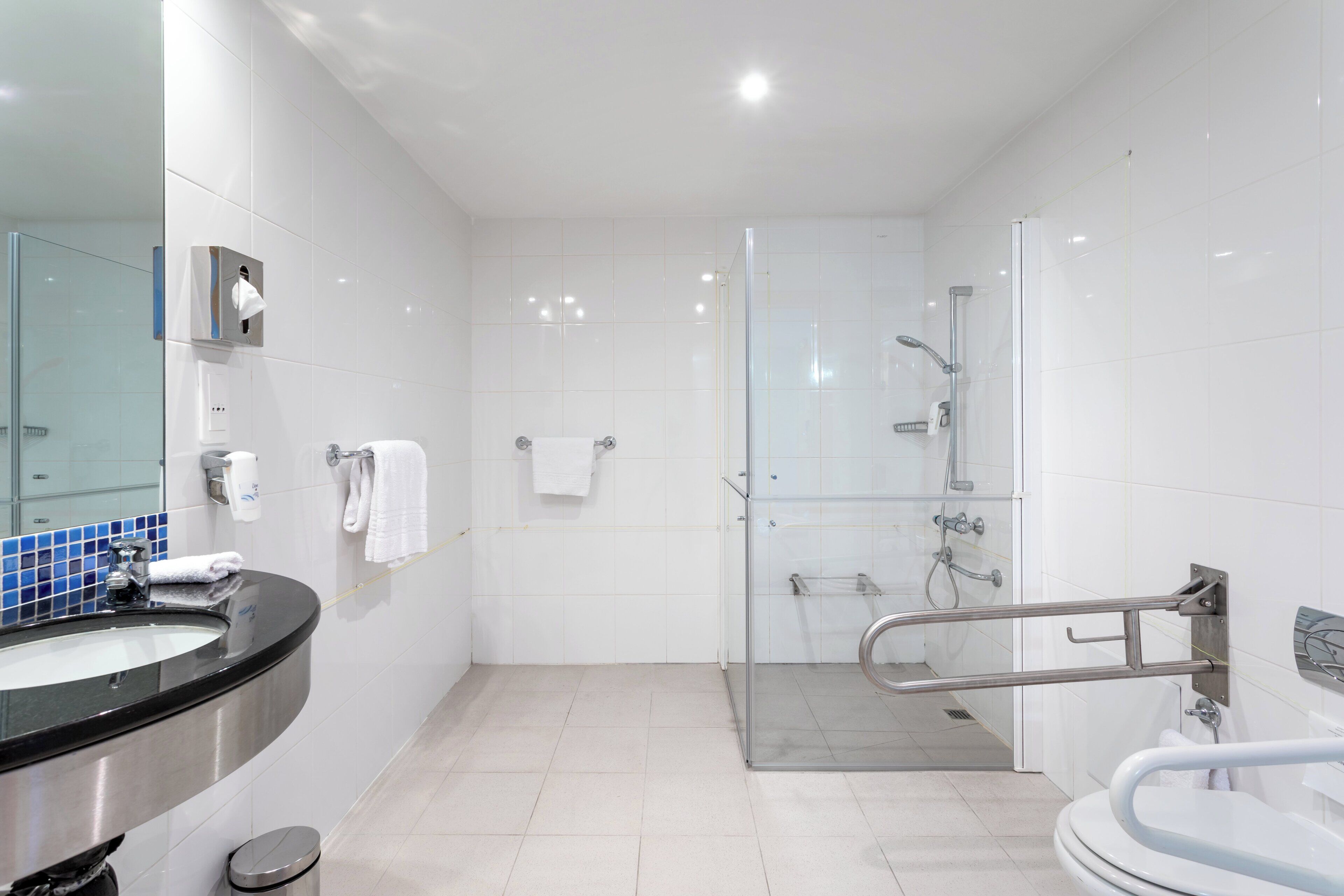 A modern bathroom with a glass shower enclosure, a black sink, and a white toilet.