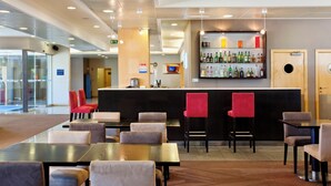 Un hall d’hôtel comprenant un bar, des espaces pour s’asseoir et un comptoir de réception.