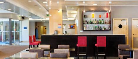 Een hotellobby met een bar, zitgedeelte en een receptiebalie.
