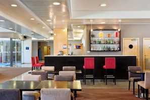 Un hall d’hôtel comprenant un bar, des espaces pour s’asseoir et un comptoir de réception.