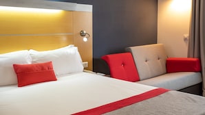 Una habitación de hotel con cama, sofá y mesita de noche.