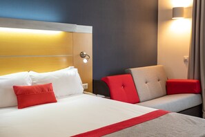Une chambre d’hôtel avec un lit, un canapé et une table de chevet.
