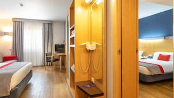 Une chambre d’hôtel avec deux lits, un bureau, une chaise, un téléphone et un miroir.