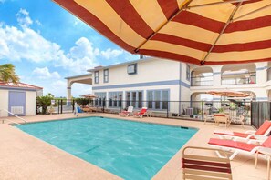 Una piscina al aire libre, sombrillas, sillones reclinables de piscina