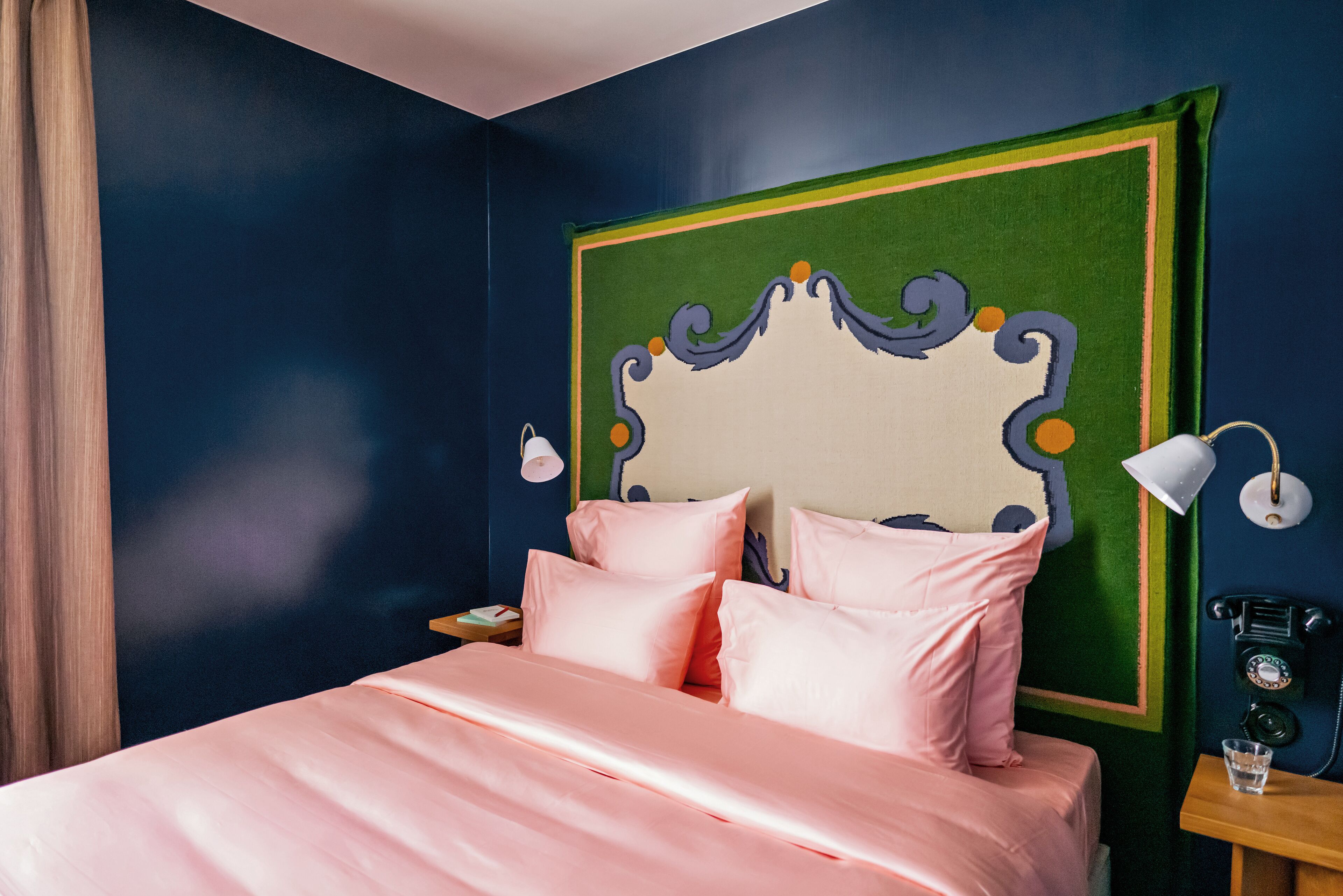 A bedroom with a bed, a nightstand, a lamp, and a telephone.
