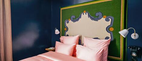 A bedroom with a bed, a nightstand, a lamp, and a telephone.