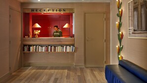 Un área de recepción con un mostrador de madera, una pared roja y una estantería llena de libros.