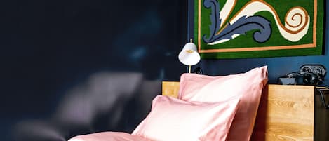 A bed with pink bedding, a wooden headboard, and a wall with a colorful abstract painting.