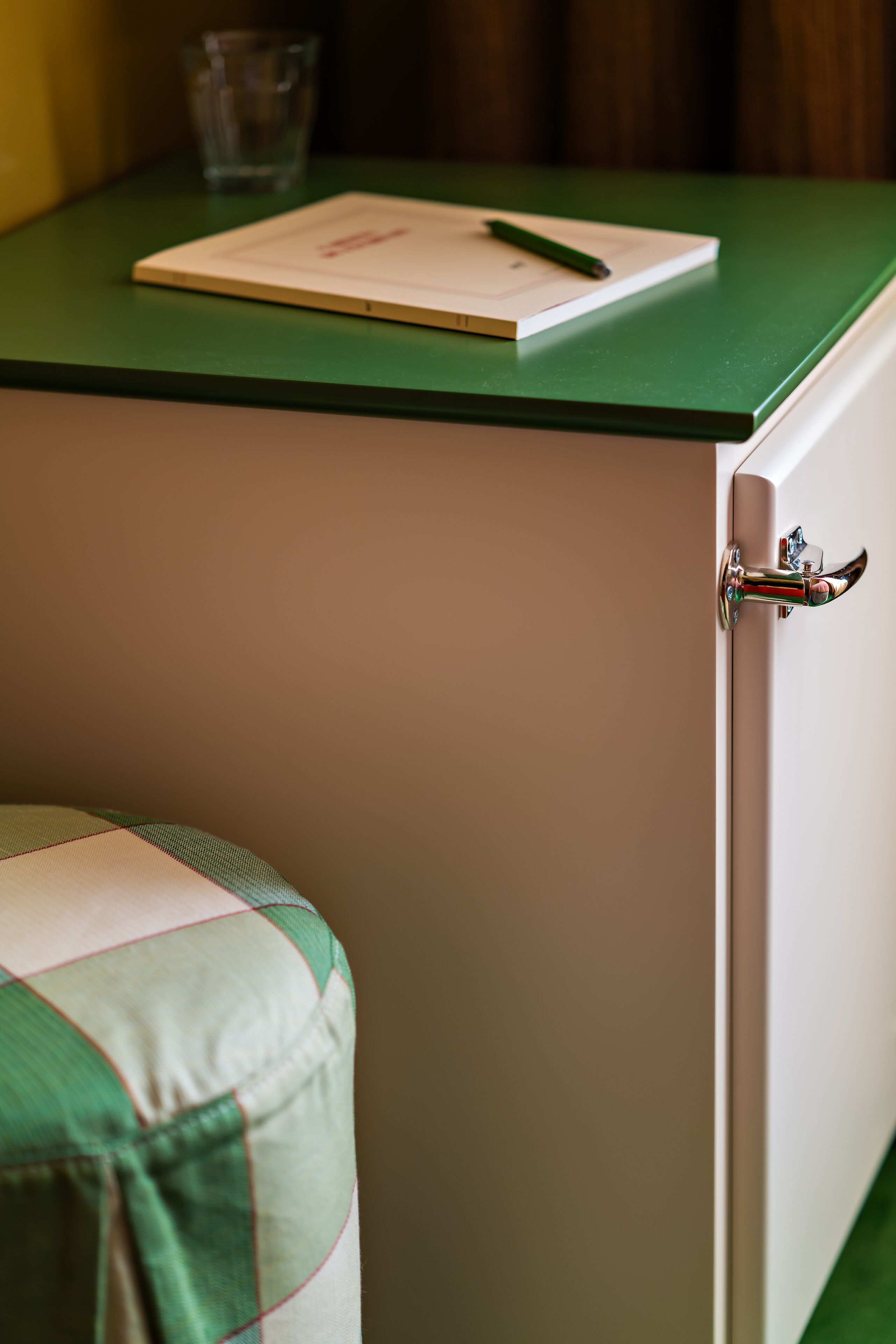 A green countertop with a notebook and pen, a glass, and a door with a handle.