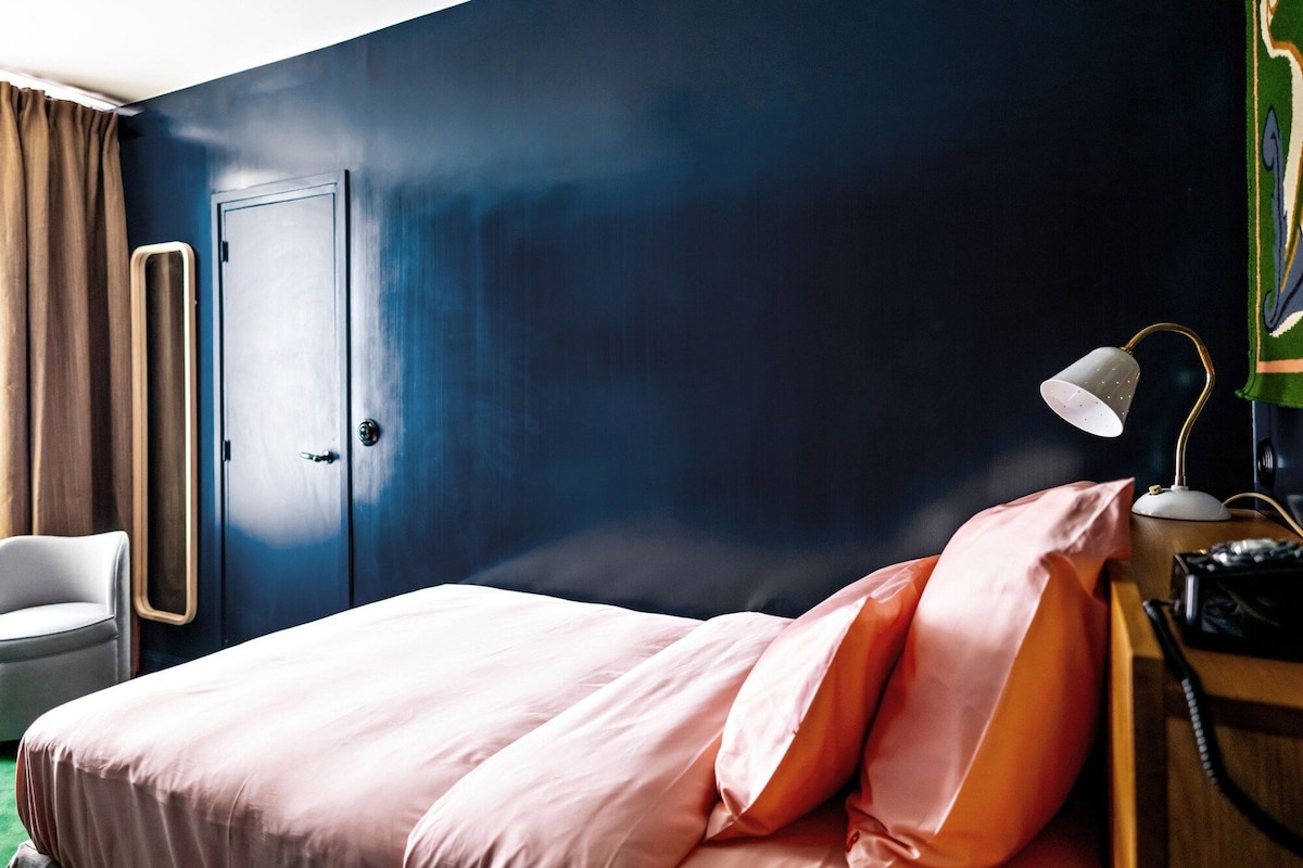 Une chambre d’hôtel comprenant un lit, un bureau avec une lampe, un téléphone et une armoire.