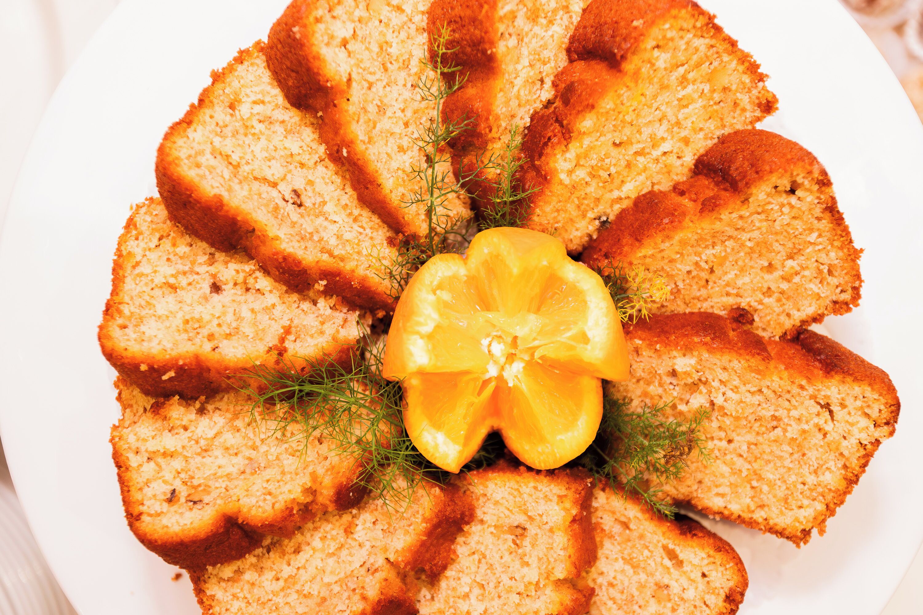 Une assiette de tranches de pain disposées en cercle, garnie d’une tranche de citron et d’herbes aromatiques.
