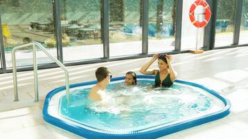 A swimming pool with a lifebuoy, metal ladder, and a view of the outside through large windows.