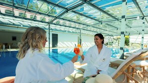 Ein Poolbereich mit Glasfassade, Liegestühlen und einem Korbstuhl-Tisch.