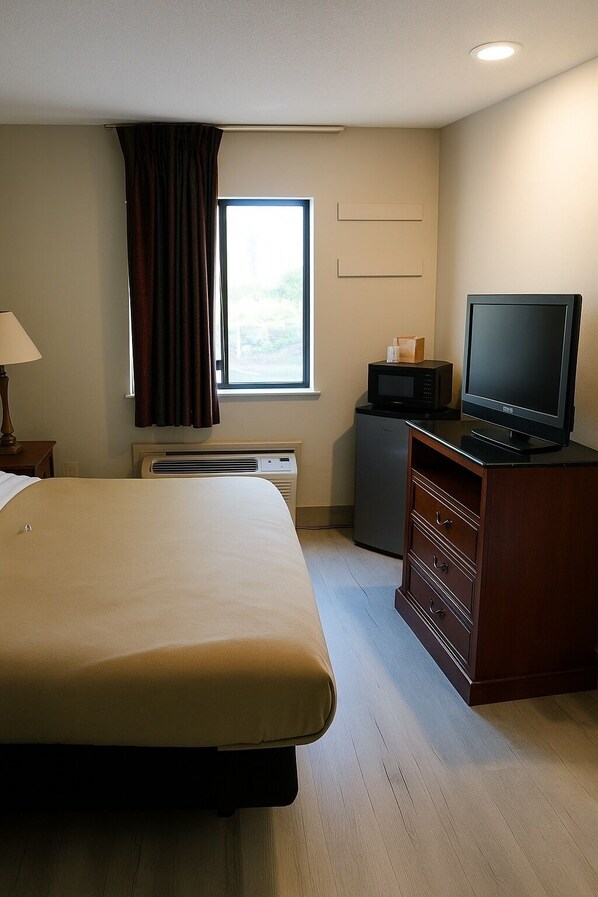 A hotel room with a large bed, a television, a microwave, and a small desk.
