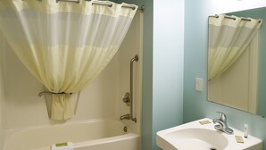 A bathroom with a bathtub, a sink, and a mirror.