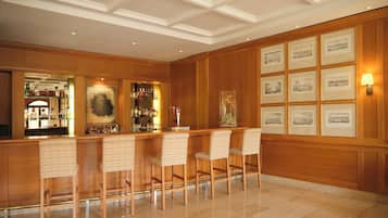 Angolo bar con rivestimenti in legno, pavimento lucidato e opere d'arte incorniciate al muro.