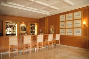 Uma área de bar com painéis de madeira, piso polido e obras de arte emolduradas na parede.