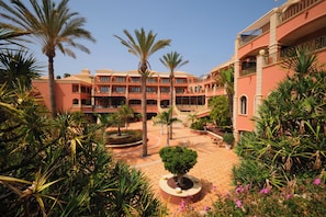 Een hotel binnenplaats met palmbomen, een fontein in het midden en een betegelde vloer.