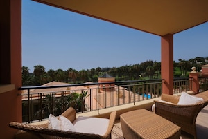 Un balcón con mobiliario de mimbre, una piscina y vista a un campo de golf.