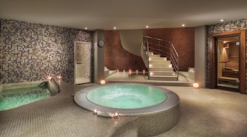 Un área de spa con una bañera de hidromasaje, una escalera y una sauna de madera.