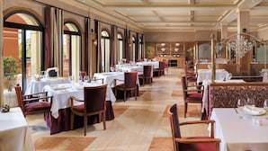 Ein geräumiges Restaurant mit mehreren Tischen und Stühlen, großen Fenstern und einer klassischen Inneneinrichtung.