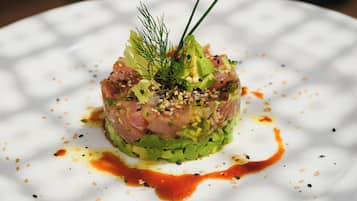 Een bord met een garnering van groene bladeren en saus.
