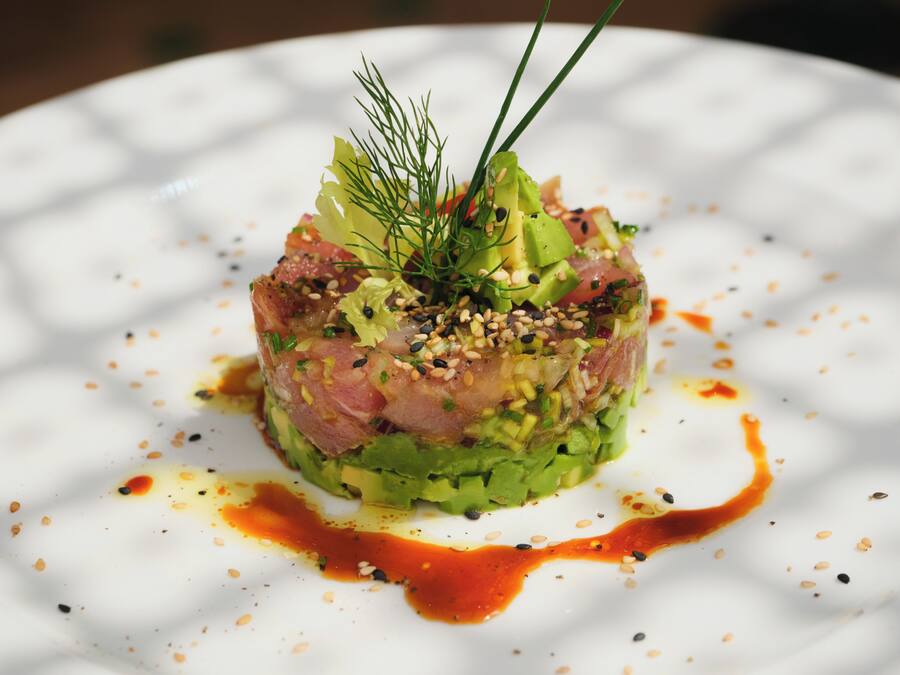Een bord met een garnering van groene bladeren en saus.