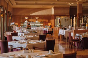 Un restaurante con varias mesas y sillas, una zona de bufé y una barra.